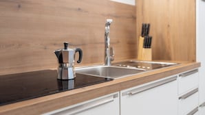 A modern kitchen with a wooden countertop, stainless steel sink, and a coffee maker.