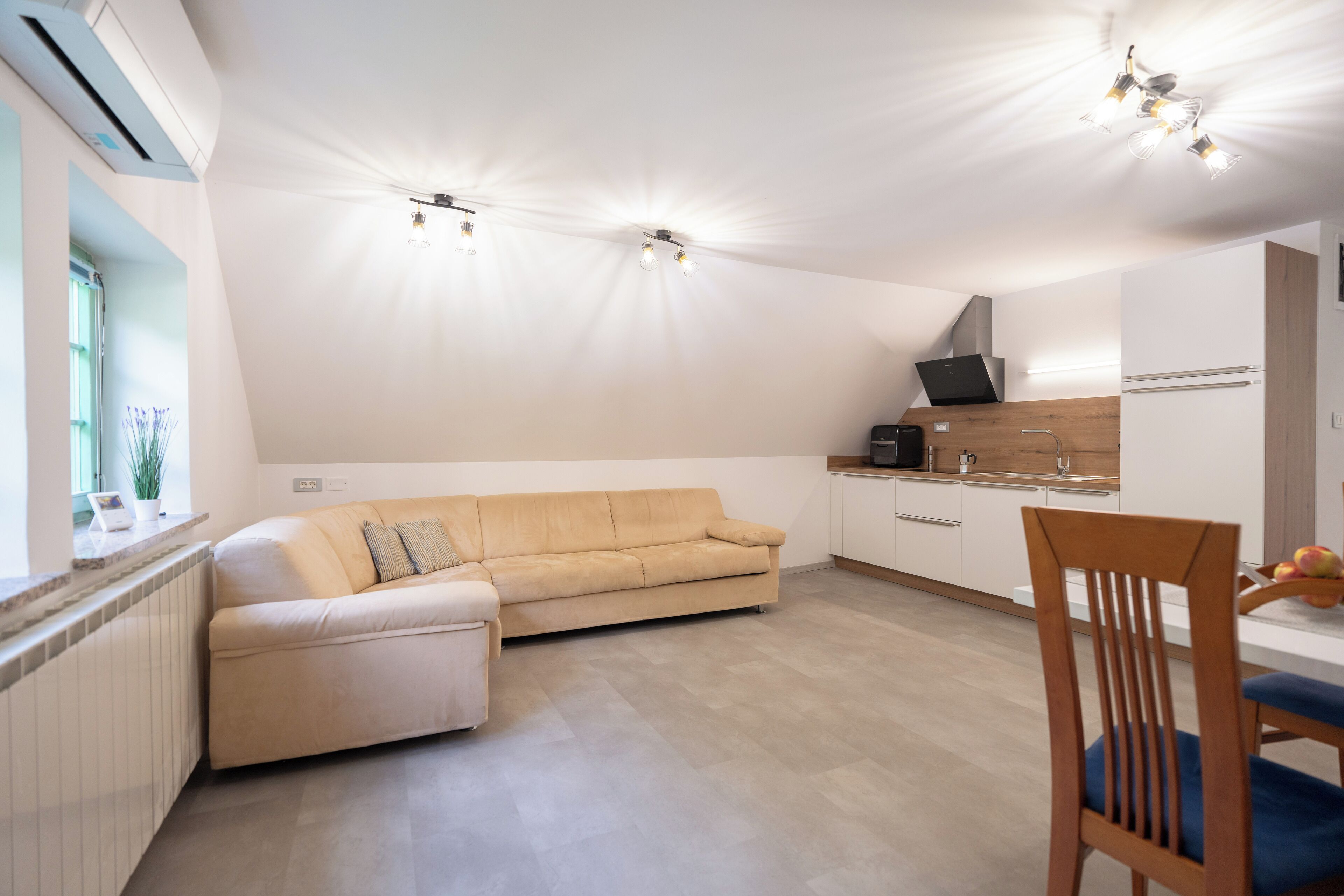 Una cocina moderna con sofá beige, mesa de comedor de madera y electrodomésticos integrados.