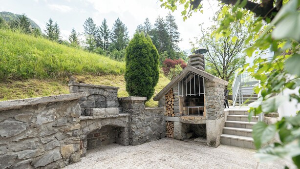 A rustic stone structure with a chimney, a stone wall, and a staircase leading up to a wooden door. - Cosy apartment for 2 persons in mountain area (Log pod Mangrtom)