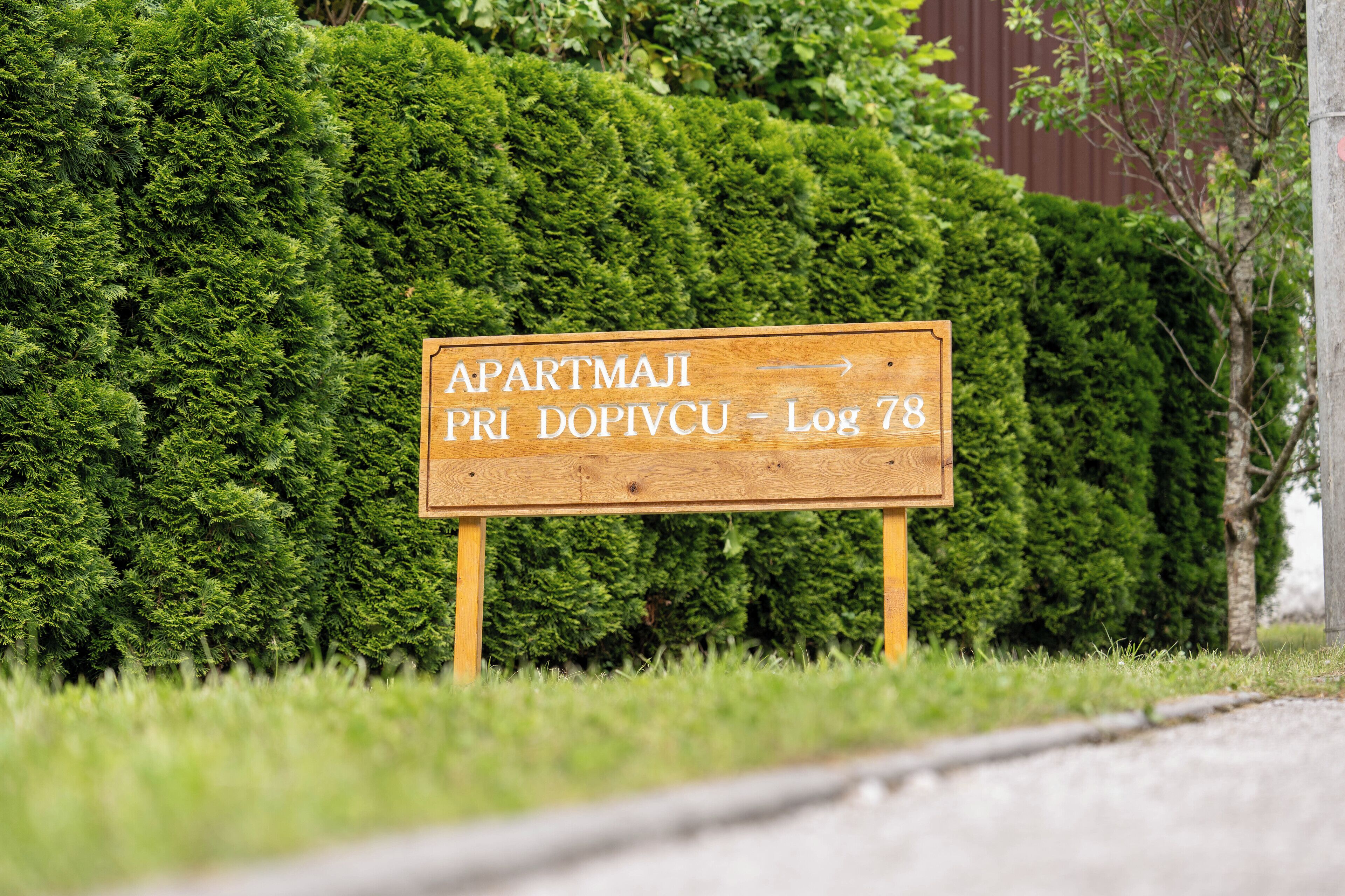 Indicador de fusta amb la inscripció 'Apartmanji Pri Dovicu - Log 78'.