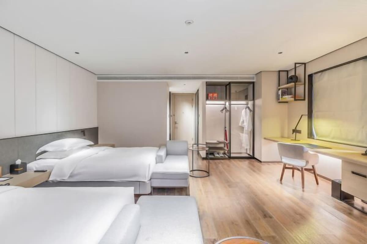 Una habitación de hotel moderna con dos camas, un escritorio y un vestidor.