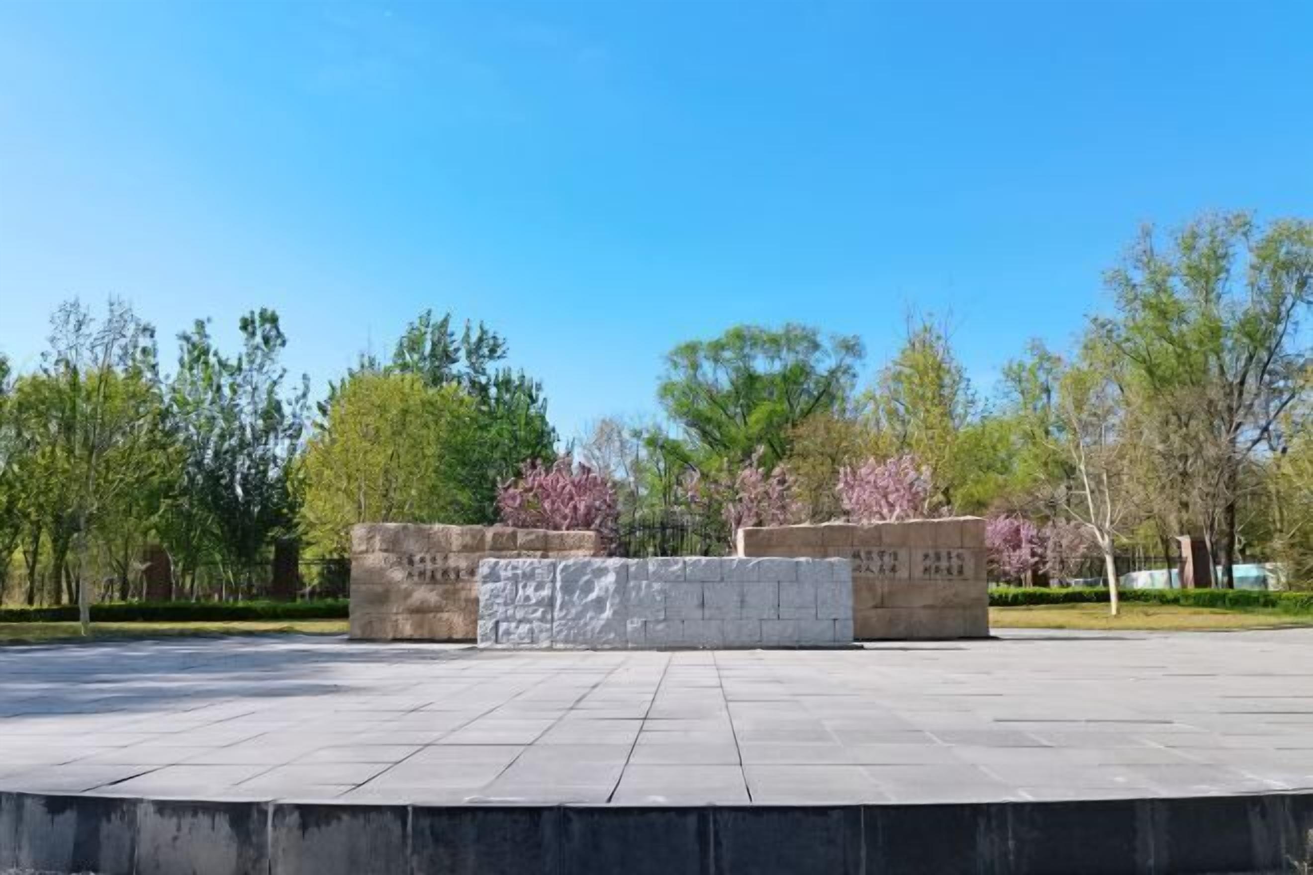 A spacious outdoor area with a paved floor, surrounded by trees and a stone structure.