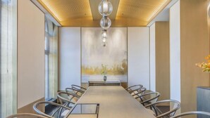 A conference room with a long table, chairs, a chandelier, and a large abstract painting on the wall. - Xiongan Kapok Hotel (Xiong County)