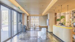 A modern reception area with a counter, seating, and large windows. - Xiongan Kapok Hotel (Xiong County)