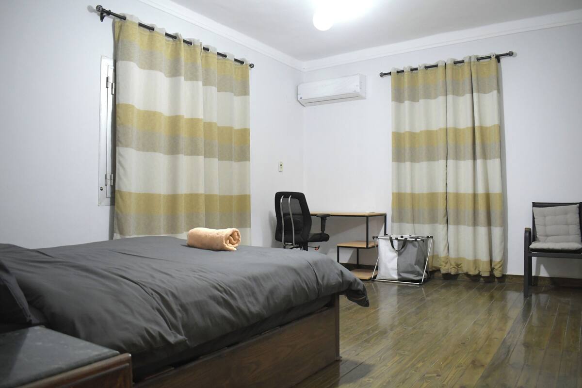 A bedroom with a bed, a desk, a chair, and a wardrobe.