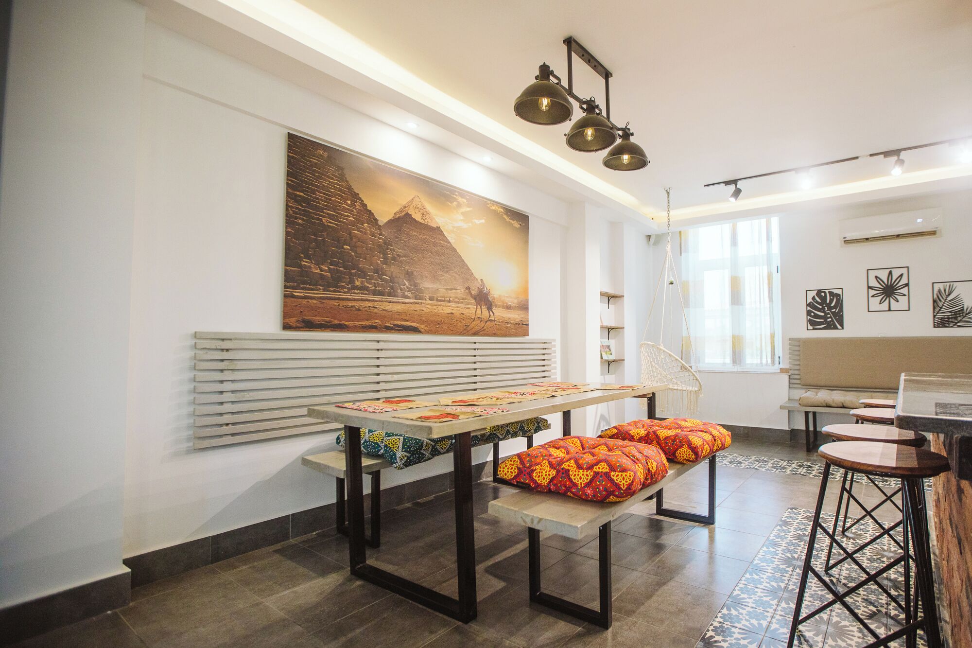 A modern interior with a long table, benches, and hanging lights.