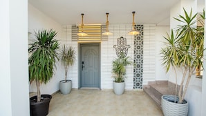 A modern entrance with a grey door, potted plants, and decorative wall panels. - Arabian Nights - Modern Duplex Villa (6th of October City)