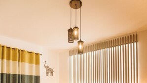 A modern bedroom with a bed, bedside tables, a rug, a striped curtain, and a wall-mounted light fixture. - Arabian Nights - Modern Duplex Villa (6th of October City)
