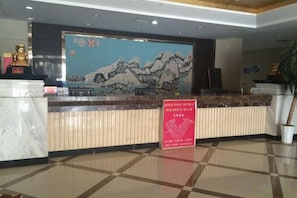A reception desk with a traditional mural, a statue, and a signboard. - Changshou Business Hotel (Luntai)