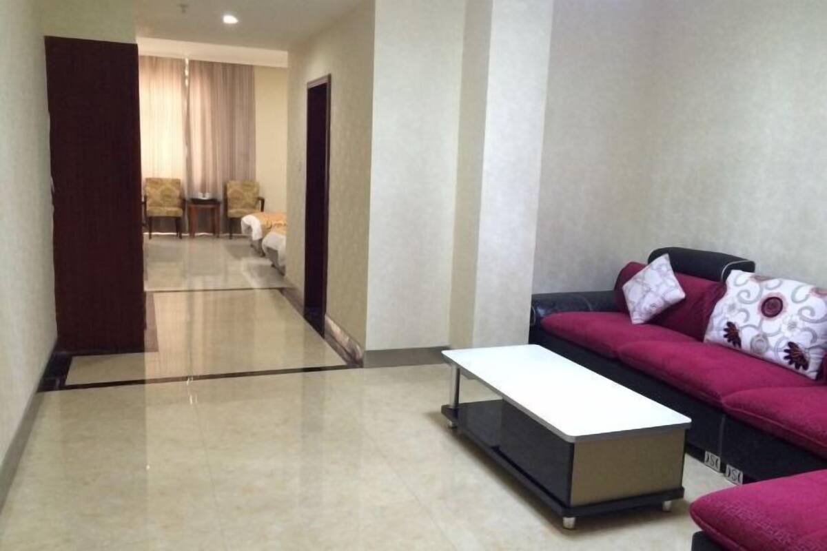 Une chambre d’hôtel avec un canapé, une petite table, une porte et une vue sur une autre chambre.