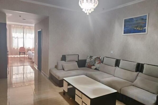 A living room with a sectional sofa, a coffee table, and a chandelier.
