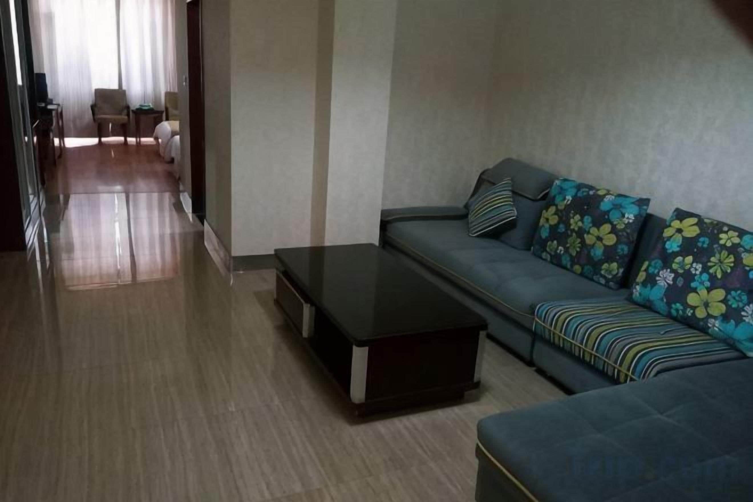 A modern living room with a sofa, a coffee table, and a view of a hallway leading to a dining area.