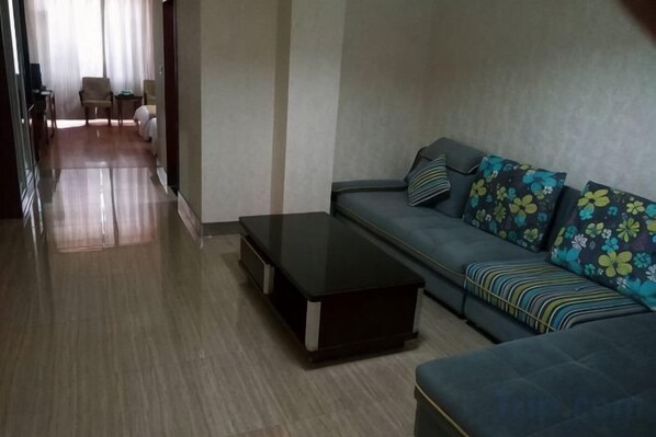 A modern living room with a sofa, a coffee table, and a view of a hallway leading to a dining area.