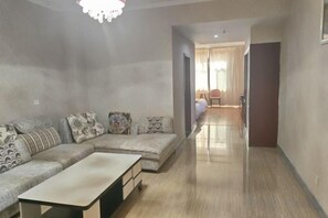 A living room with a sofa set, a coffee table, and a hallway leading to another room. - Changshou Business Hotel (Luntai)