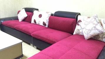 A sectional sofa with a black frame and red cushions, accompanied by patterned pillows.