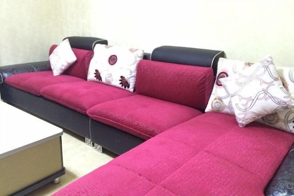 A sectional sofa with a black frame and red cushions, accompanied by patterned pillows.