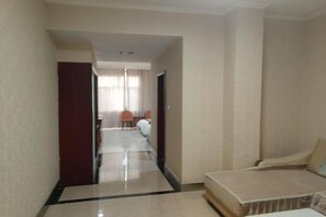 A hotel room with a bed, a chair, and a desk. There is a hallway leading to another room. - Changshou Business Hotel (Luntai)
