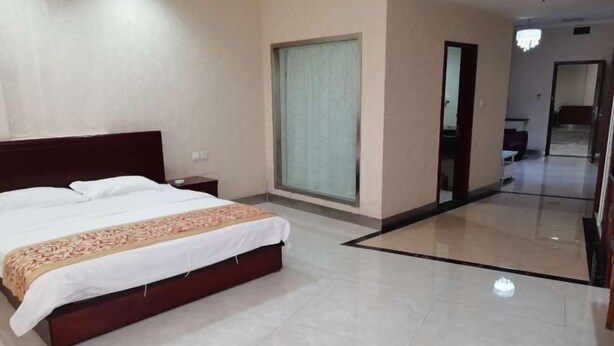 A hotel room with a bed, a nightstand, a large window, and a mirror. - Changshou Business Hotel (Luntai)