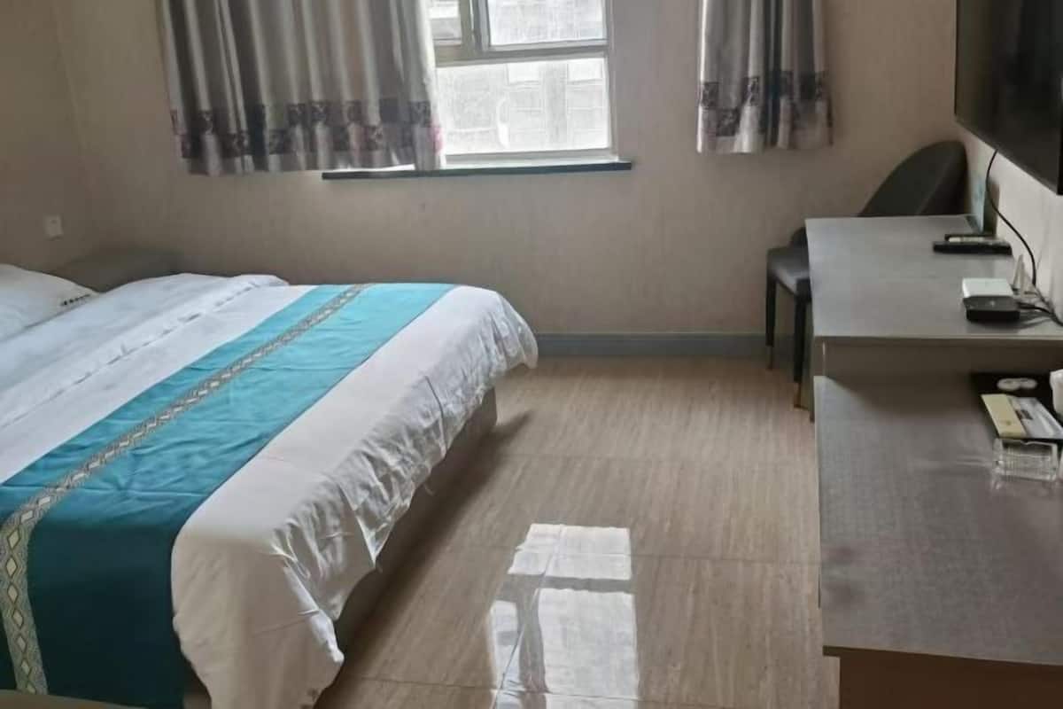Une chambre d’hôtel avec un lit, un bureau, une chaise et un téléviseur.