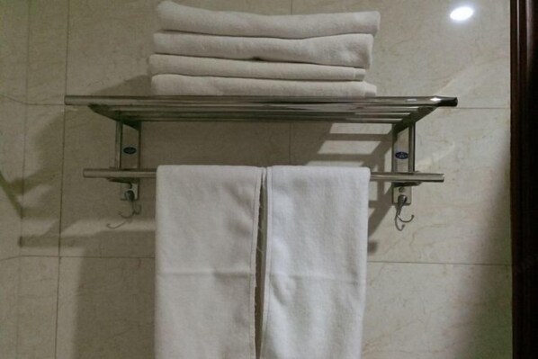 A bathroom with a towel rack holding folded towels and a towel dispenser. - Changshou Business Hotel (Luntai)