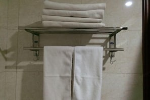 A bathroom with a towel rack holding folded towels and a towel dispenser.