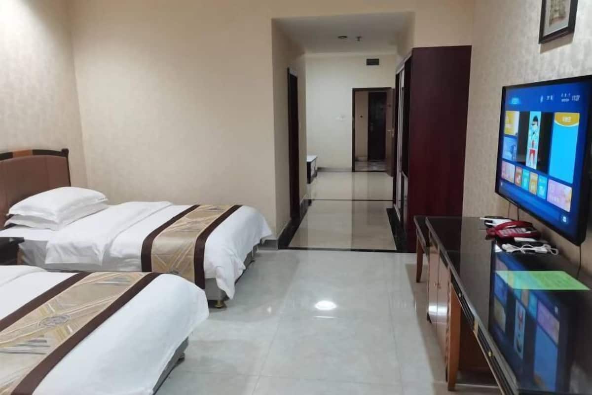 Une chambre d’hôtel avec deux lits, un téléviseur fixé au mur et un bureau avec un ordinateur.
