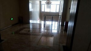 A spacious lobby with a marble floor, a patterned rug, and a glass railing. - Changshou Business Hotel (Luntai)