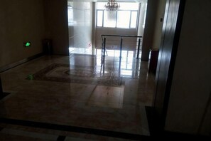 A spacious lobby with a marble floor, a patterned rug, and a glass railing. - Changshou Business Hotel (Luntai)