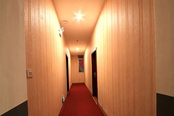 Un pasillo de hotel con paredes de madera, alfombra roja y puertas a ambos lados.