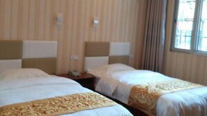 Habitación de hotel con dos camas, una ventana con cortinas y un teléfono en la mesita de noche.