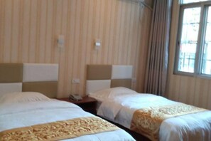 A hotel room with two beds, a window with curtains, and a telephone on the nightstand.