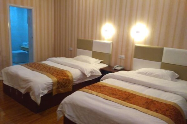 A hotel room with two single beds, each with a headboard and bedside table.