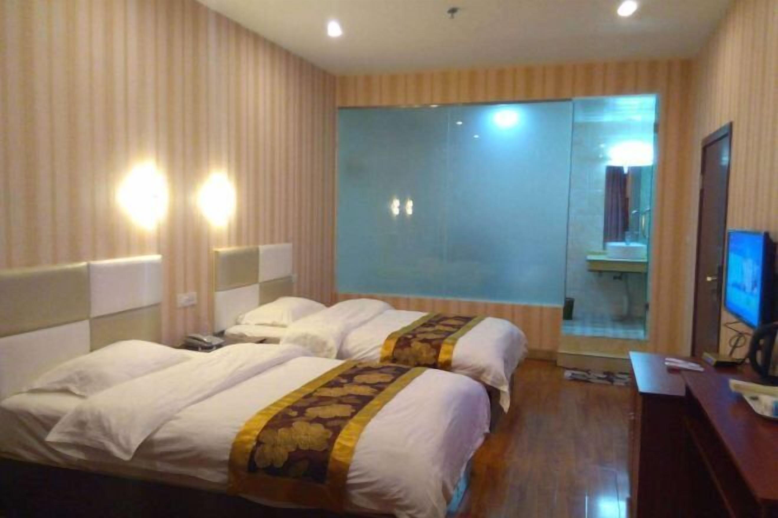 A hotel room with two beds, a large mirror, a television, and a desk.