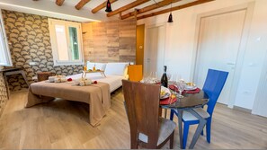 Une pièce chaleureuse avec un lit, une table à manger dressée pour deux personnes et un plafond en bois.