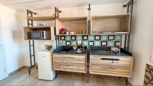 A compact kitchen with wooden cabinetry, a built-in microwave, and a small refrigerator. - Ca de la Corona by Ca-sa Check (Chioggia)
