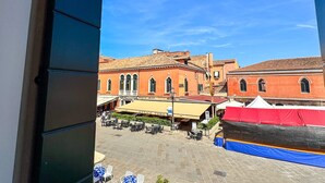 A courtyard with outdoor seating, red buildings, and a clear blue sky. - Ca de la Corona by Ca-sa Check (Chioggia)