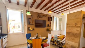 A cozy room with a dining table set for two, a sofa with cushions, and a wooden partition. - Ca de la Corona by Ca-sa Check (Chioggia)