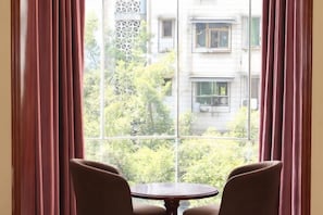 Une pièce avec une grande fenêtre, deux chaises et une petite table ronde.