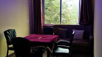 Un comedor con mesa y sillas, un sofá y una ventana con cortinas.