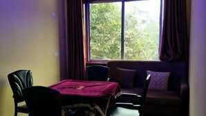 A room with a table, two chairs, a sofa, and a window with curtains. - Shuangqiao District Haoshen Hotel (Chongqing)