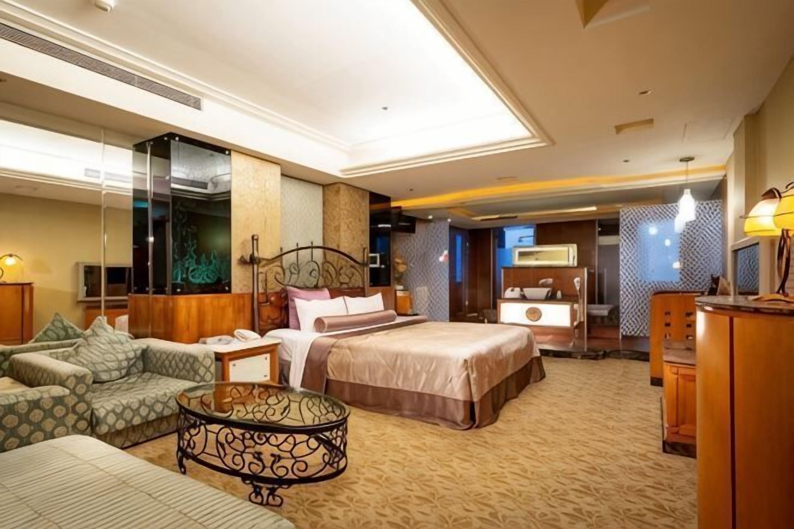 A hotel room with a bed, a sofa, a coffee table, a desk, and a TV.
