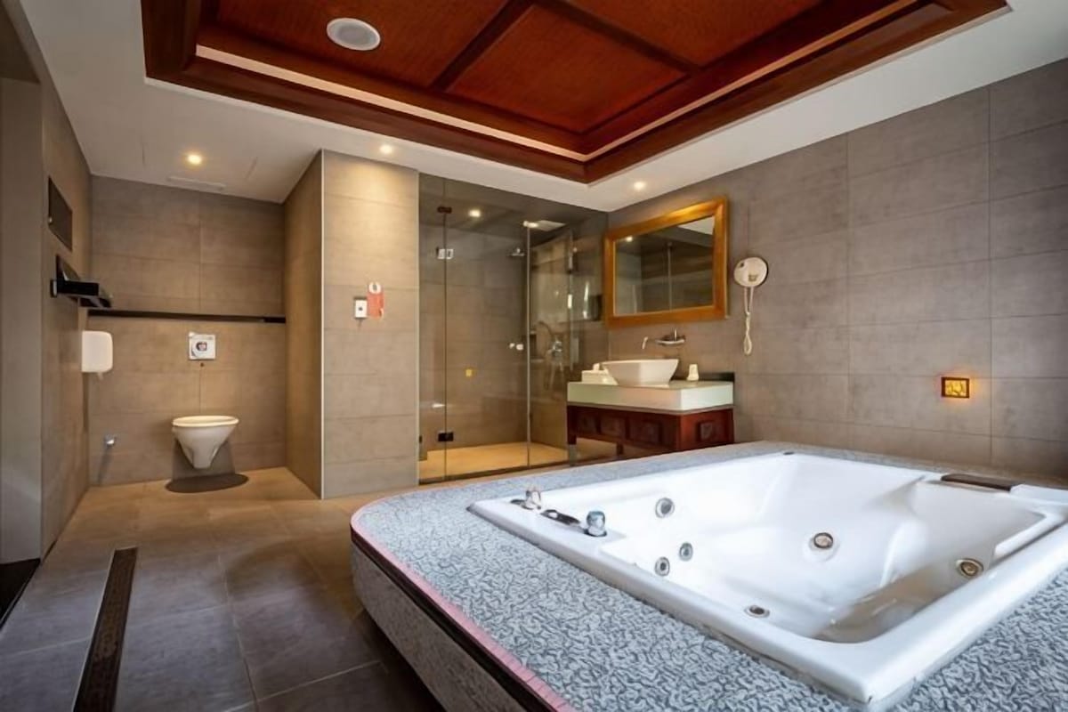 A modern bathroom with a large bathtub, a shower, and a vanity with a mirror.