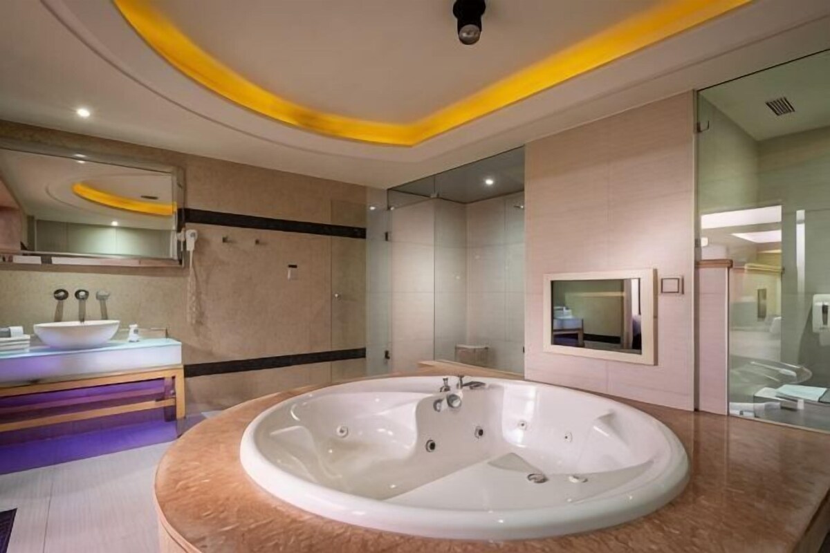 A modern bathroom with a large bathtub, a vanity with a mirror, and a glass shower enclosure.