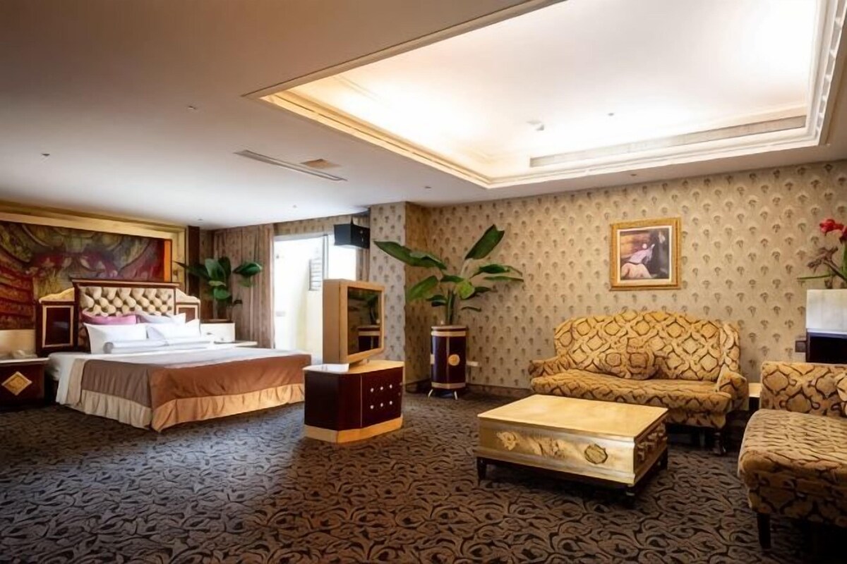 Een hotelkamer met een bed, een bank, een fauteuil en een salontafel.