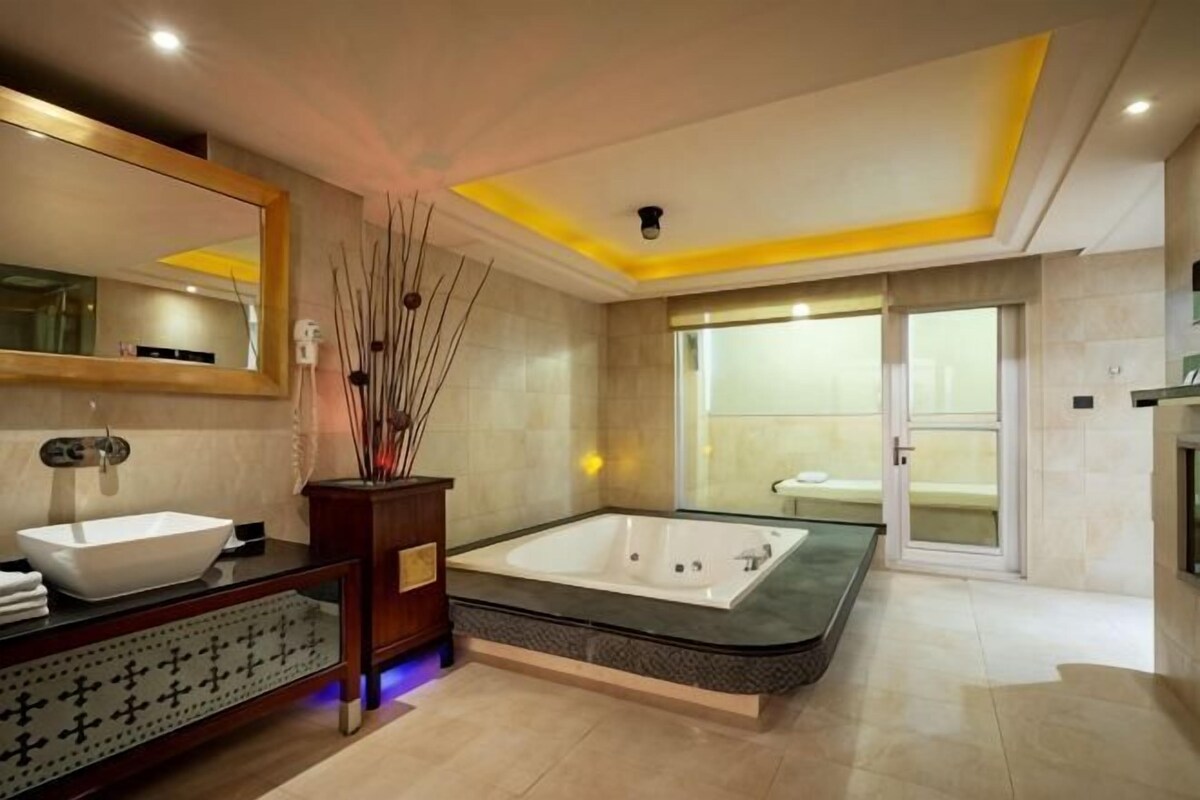 A modern bathroom with a large bathtub, a vanity with a sink, and a mirror.