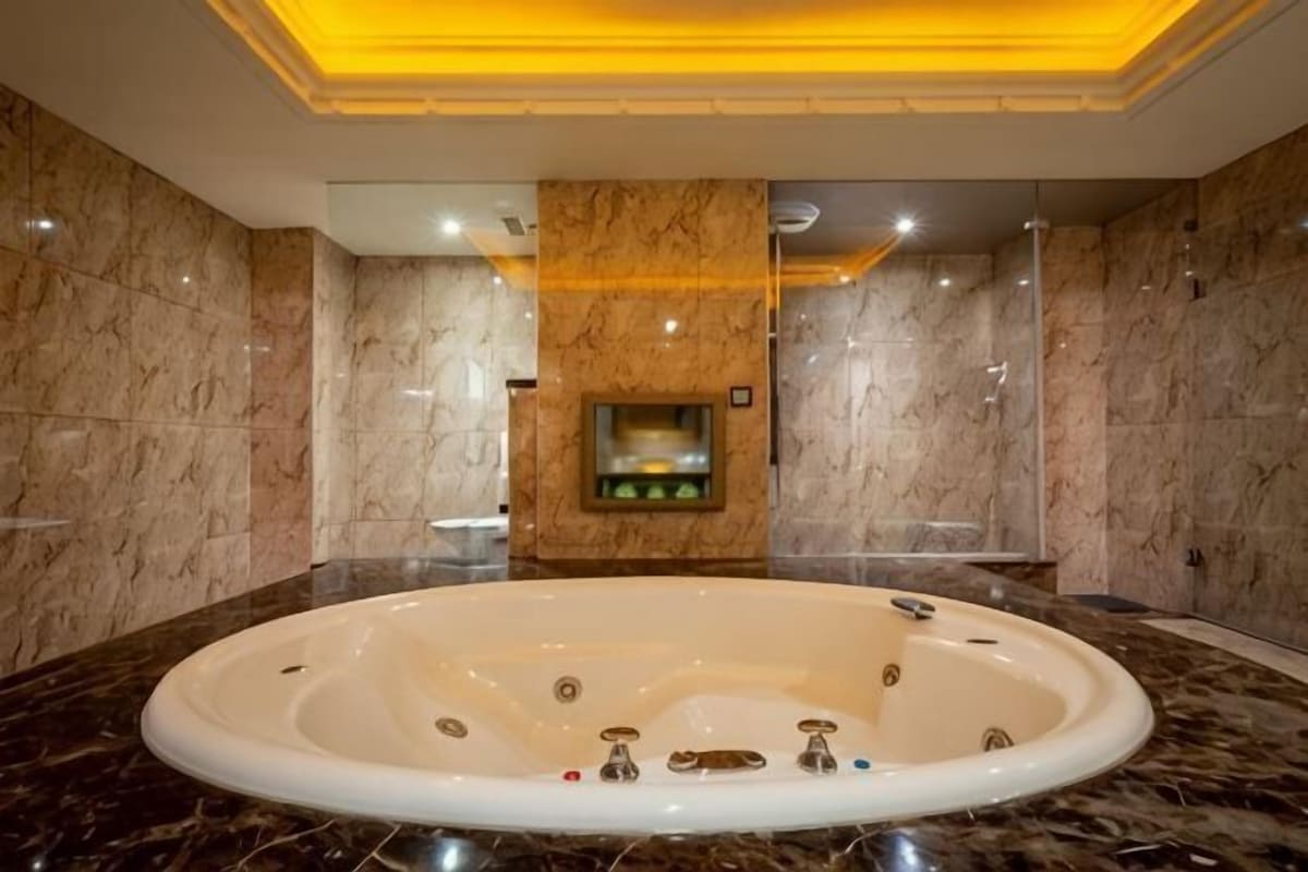 A large oval bathtub in a bathroom with marble walls and a central column.