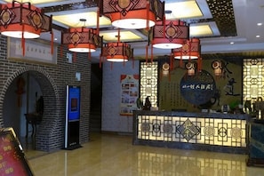 A hotel lobby with a reception desk, hanging lanterns, and a wall with calligraphy. - Youyicun Hotel (Pingdu)