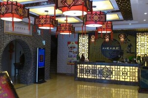 Un área de recepción con pared de ladrillo, una puerta azul y un mostrador decorativo con motivos chinos tradicionales.