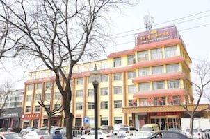 Un hotel de varios pisos con fachada amarilla, múltiples ventanas y un letrero que indica un restaurante en la planta baja.