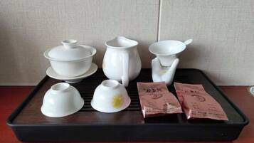 Una bandeja con juego de té de cerámica blanca, que incluye tetera, tazas y platillos, junto a dos bolsitas de té.
